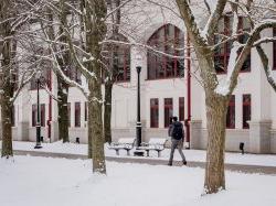 Student walking along the pathway next to the Student Center Quad in the snow.